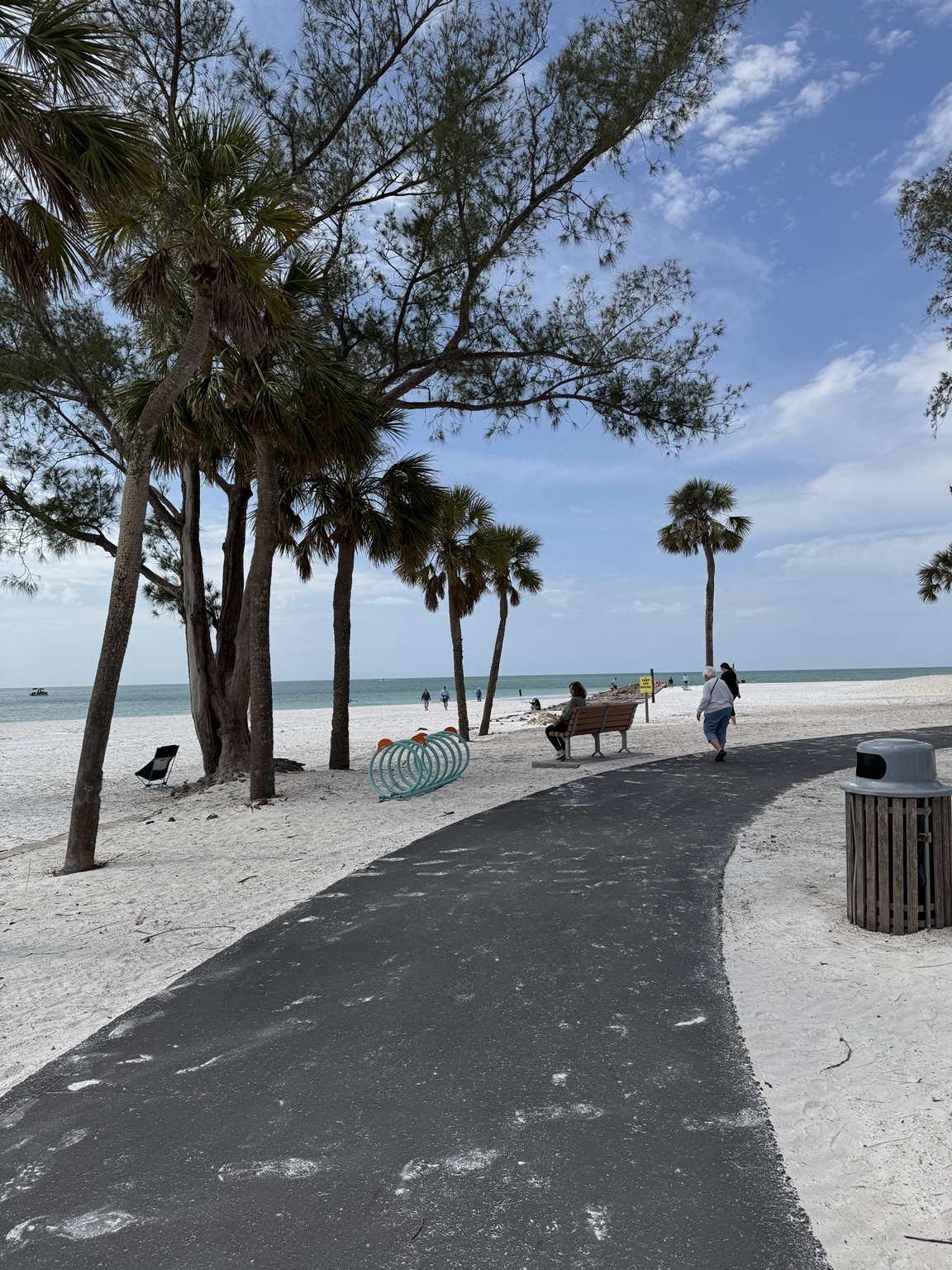 Palm trees and a winding path leading toward the white sand at Coquina Beach