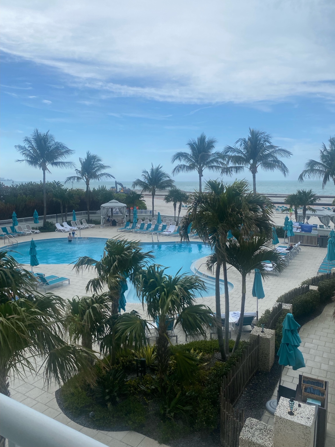 Lido Beach Resort pools framed by palm trees with Lido Beach and the Gulf beyond