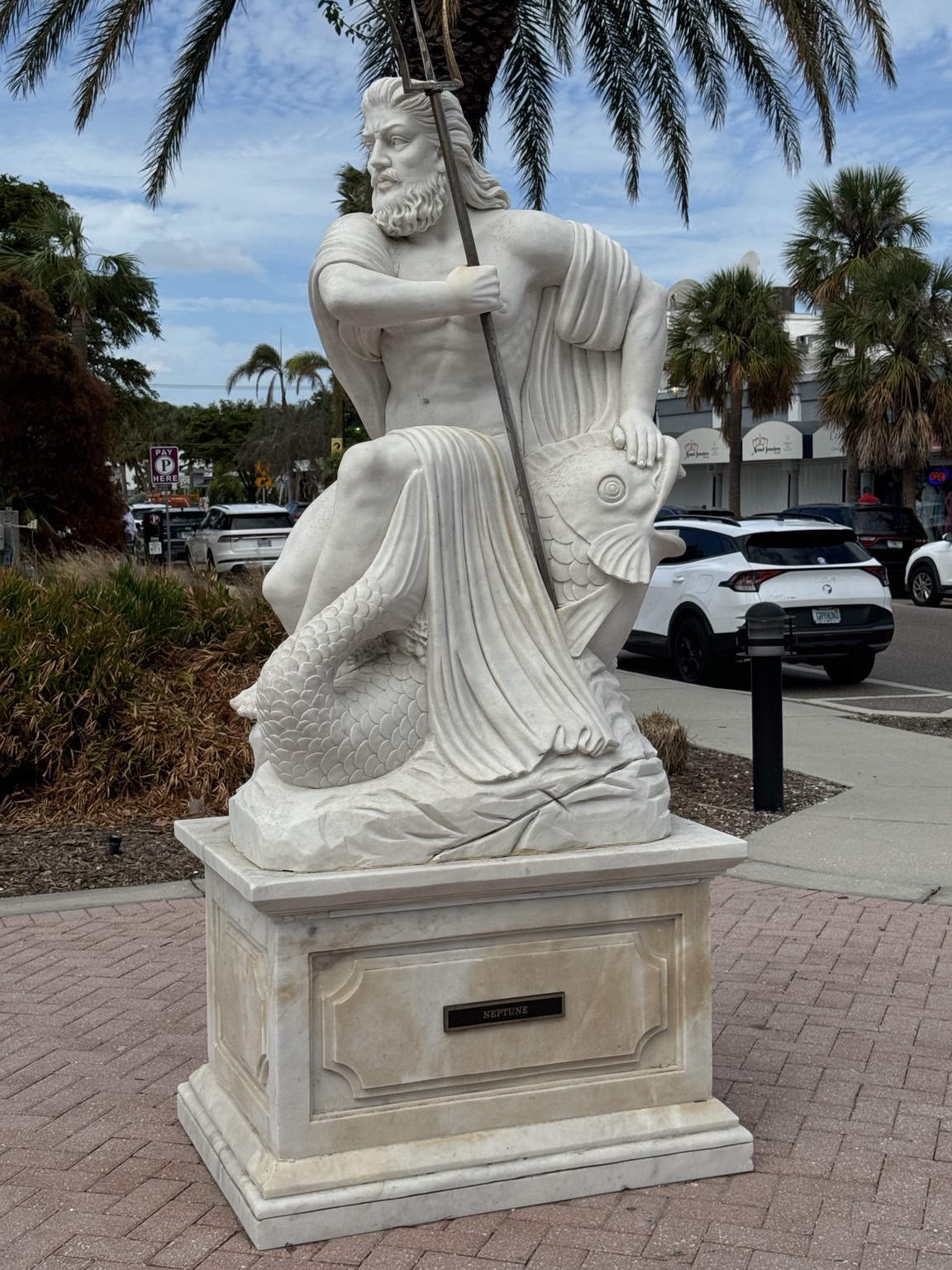 A white marble statue of Neptune holding a trident at St. Armands Circle