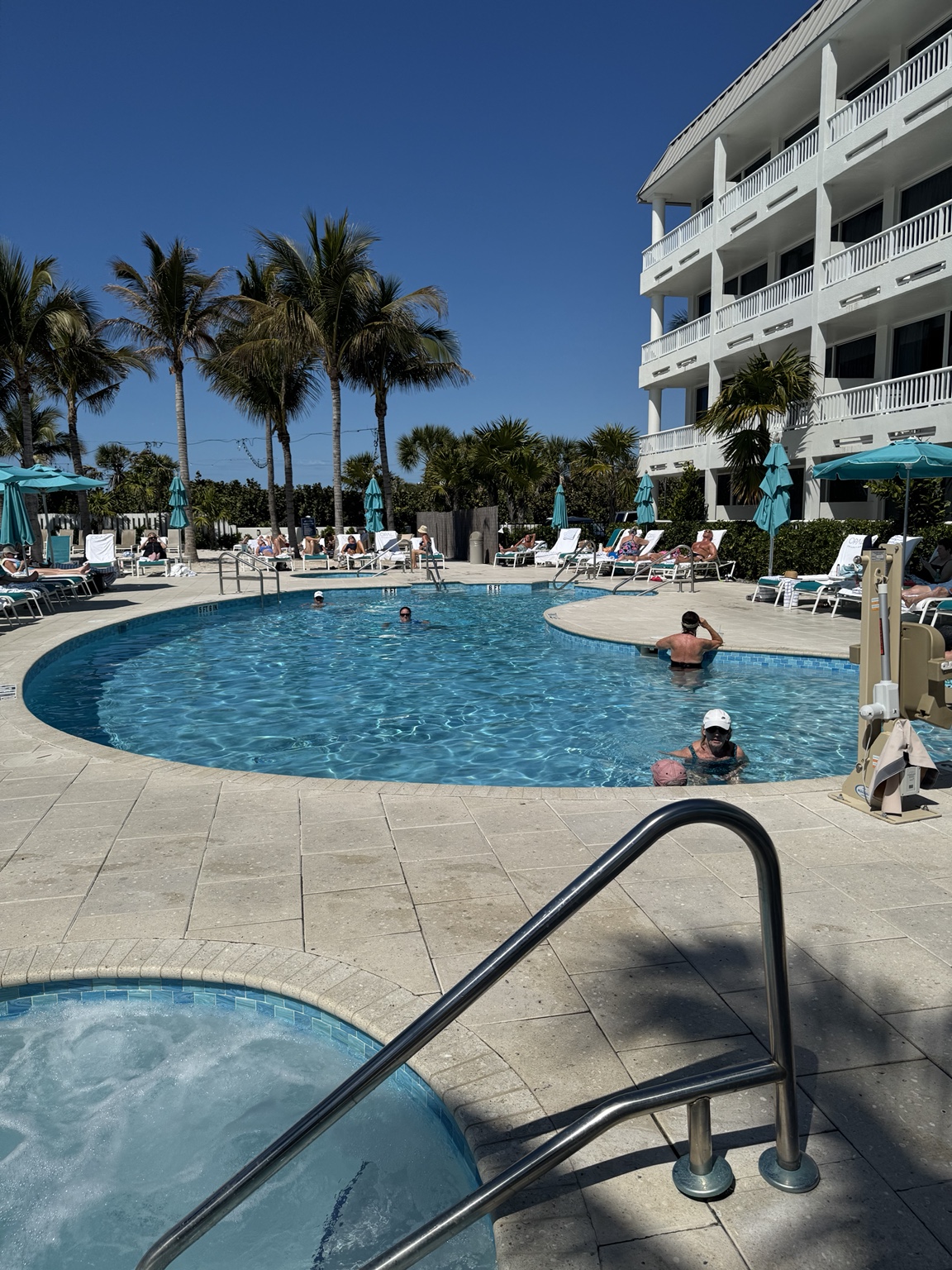 A curving blue pool surrounded by palms and guest rooms at Lido Beach Resort