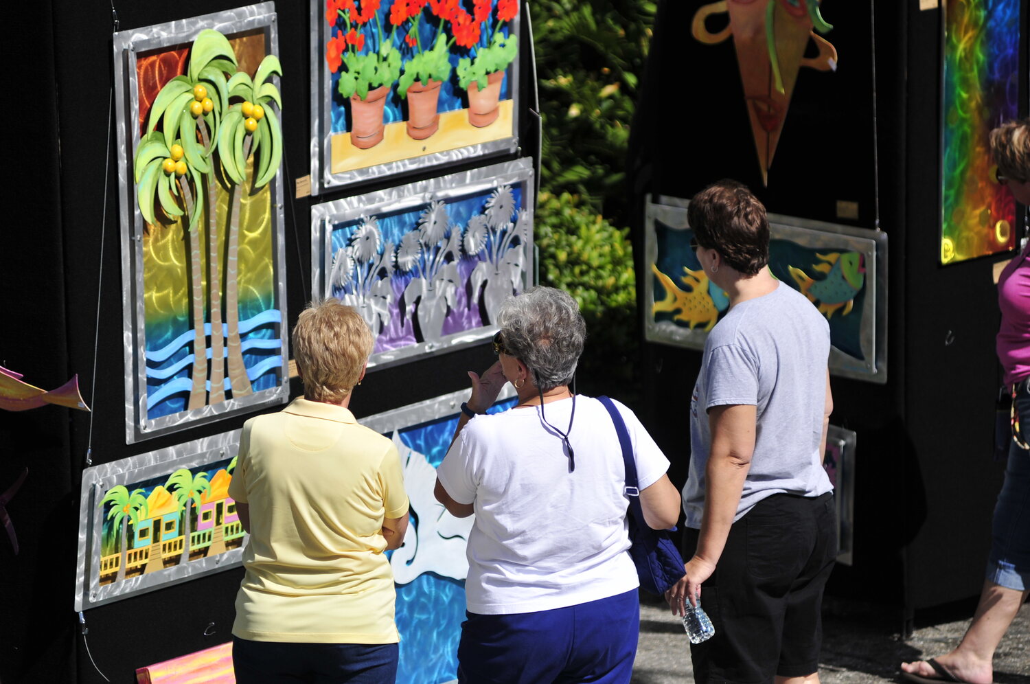 Visitors looking at colorful metal artwork at an outdoor art festival
